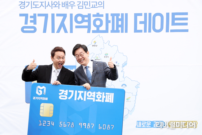 수원시 남문시장에서 열린 ‘경기지역화폐 체험 데이트’ 행사에서 이재명 경기도지사와 배우 김민교씨가 경기지역화폐카드 보드를 들고 기념촬영을 하고 있다.
