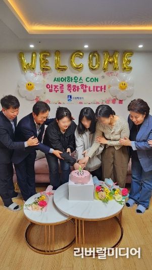 셰어하우스 6호 입주기념식에서 청년들과 참석자들이 케이크를 자르고 있다.